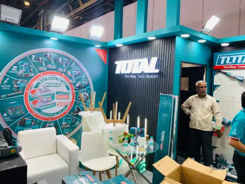 interior of TOTAL exhibition stall with branded feature wall, teal framework and visitor seating